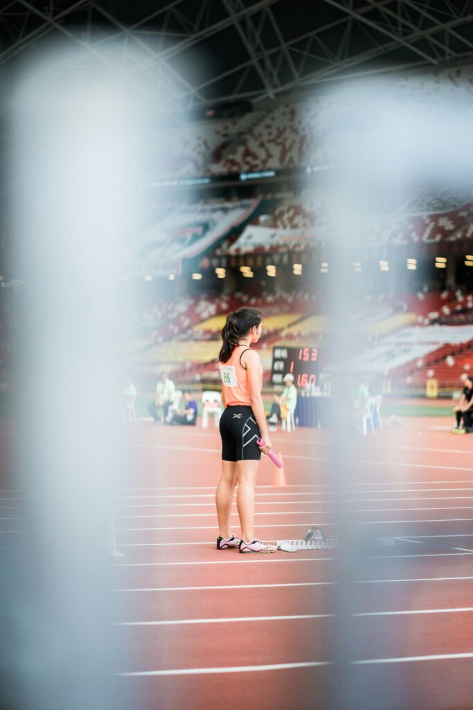 Female track athlete in starting position at the beginning of a race, eyes closed, visualizing before the start.